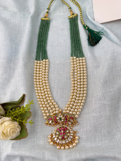 Mahilas layered pearl and green bead necklace with a traditional Jadau Kundan pendant featuring ruby and gold accents.